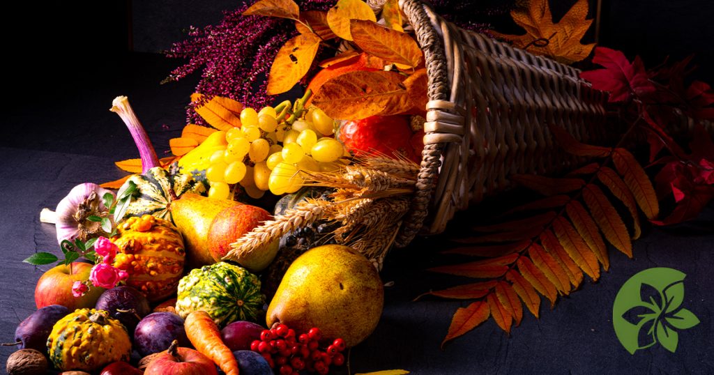 Thanksgiving cornucopia of fall fruits and vegetables decorated with autumn flowers and foliage